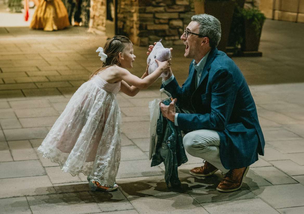 A girl in a white dress playing with her dad